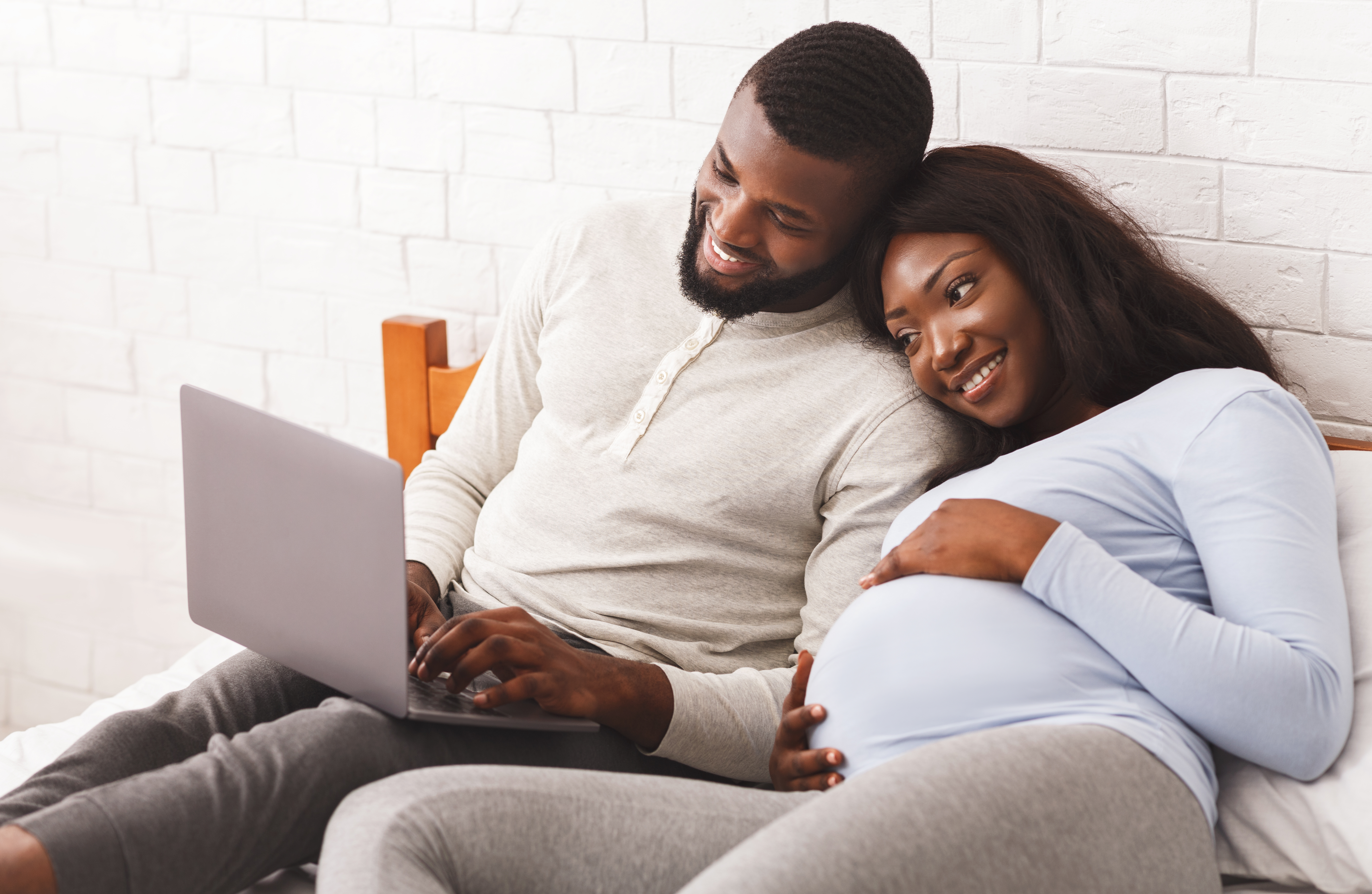 Pregnant woman and man looking at a laptop together, smiling